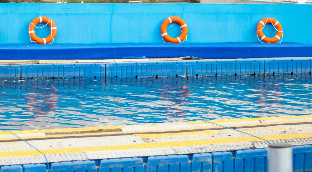 Lifebuoys mounted by a swimming pool representing water safety measures and drowning prevention