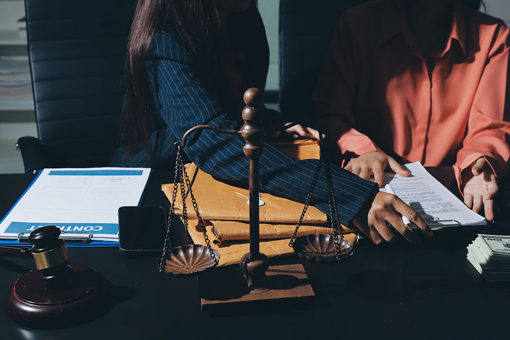 Two professionals reviewing compensation with a scale and money on a desk