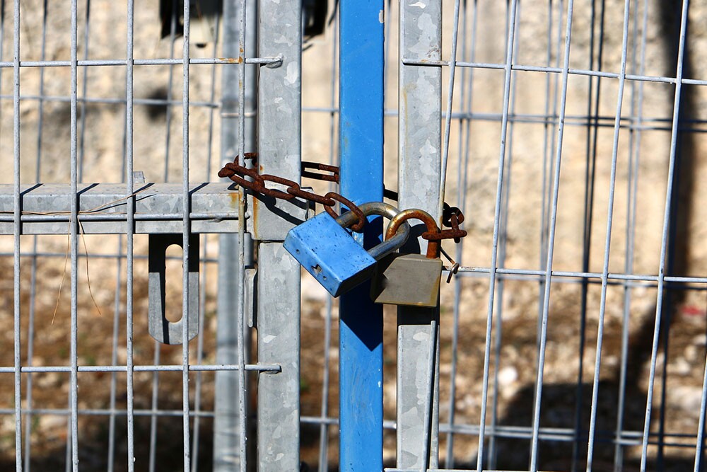 Padlock on a closed gate representing property security and restricted access conditions