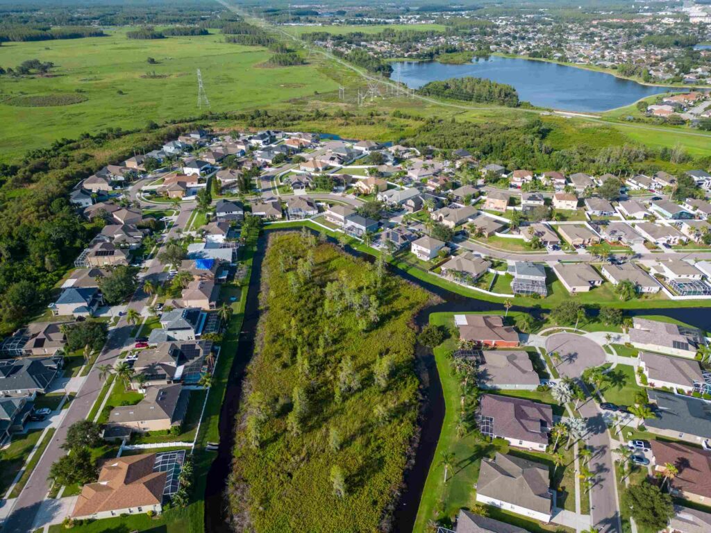 Aerial view of a residential neighborhood in New Port Richey surrounded by green spaces and a lake.