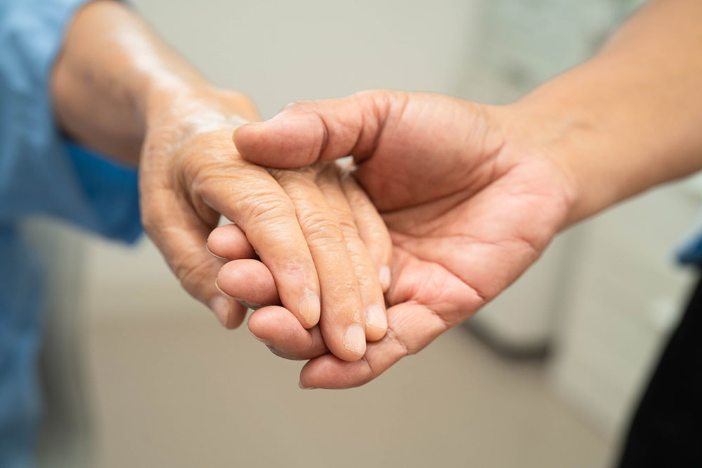 Caregiver holding an elderly woman&rsquo;s hands representing resident safety, care, and concerns about neglect or abuse